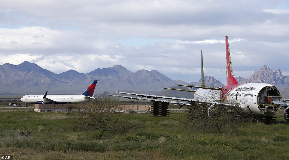 A recently landed Delta Air Lines plane is towed past two stripped passenger planes at Pinal Airpark