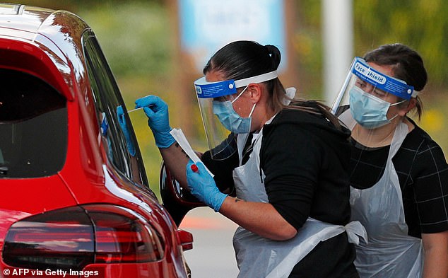 A medical worker takes a swab to test for coronavirus from a visitor to a drive-in testing facility at the Chessington World of Adventures Resort