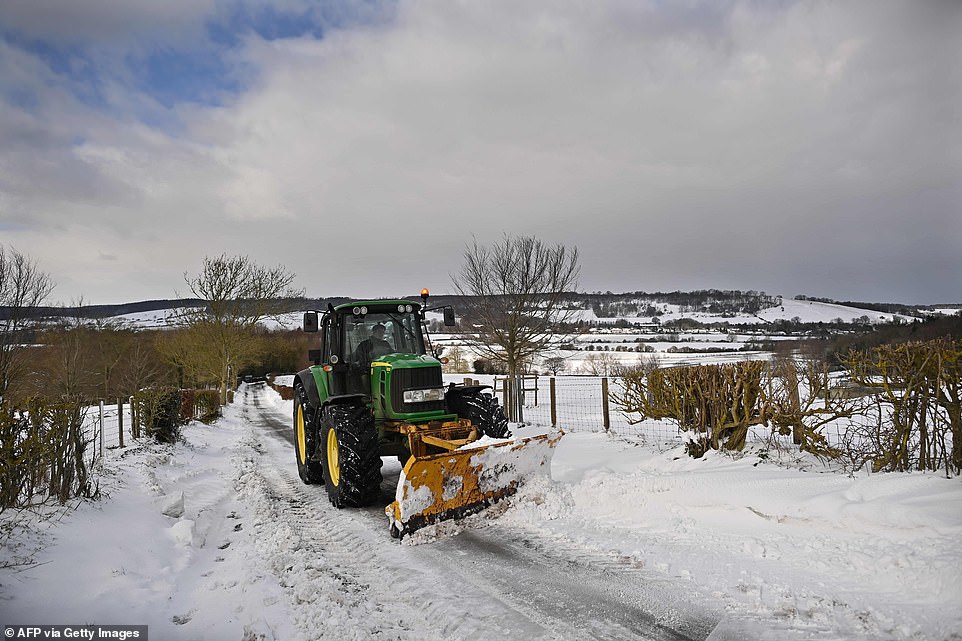 A farmer uses a snow plough to clear a country lane in Wye, south-east England as wintry weather continues to sweep across the country