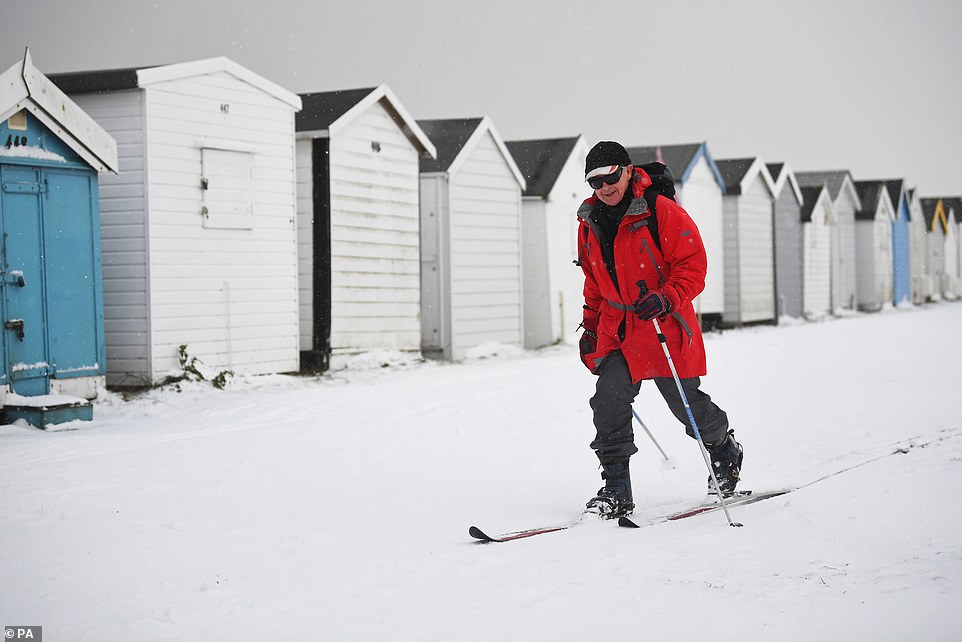 Jonathon Gittoes skis past snow covered beach huts at Thorpe Bay in Essex as bitterly cold winds continue to grip much of the nation