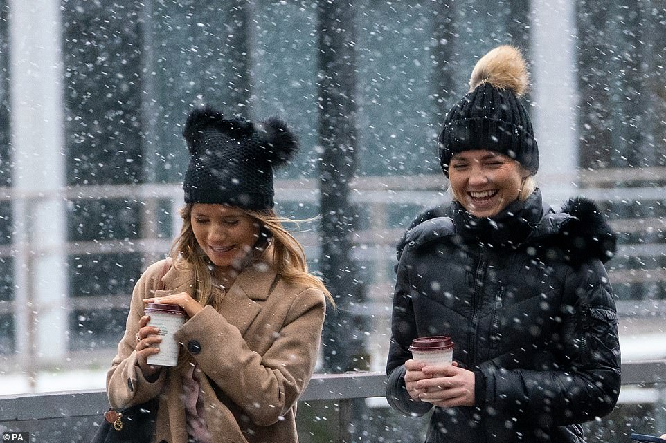 Two walkers carry Pret coffees during snow flurries in the Docklands, east London, in another wintry image taken today