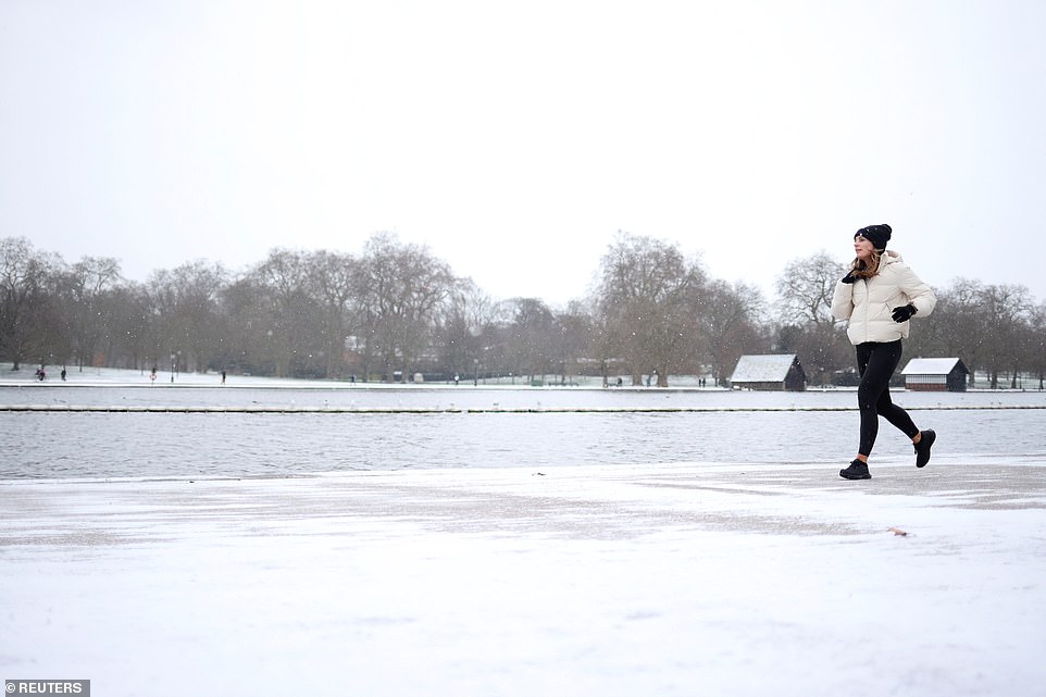 A woman jogs through a snow-covered Hyde Park in London as Storm Darcy lashes Britain
