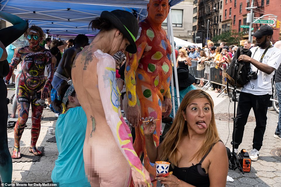 An artist sticks her tongue out as she paints a unique design onto a willing participant in the bodypainting event