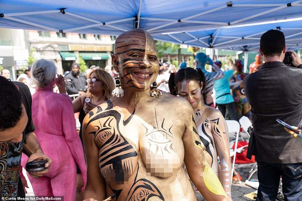 A woman shimmers in gold while other artistic lines are painted across her skin