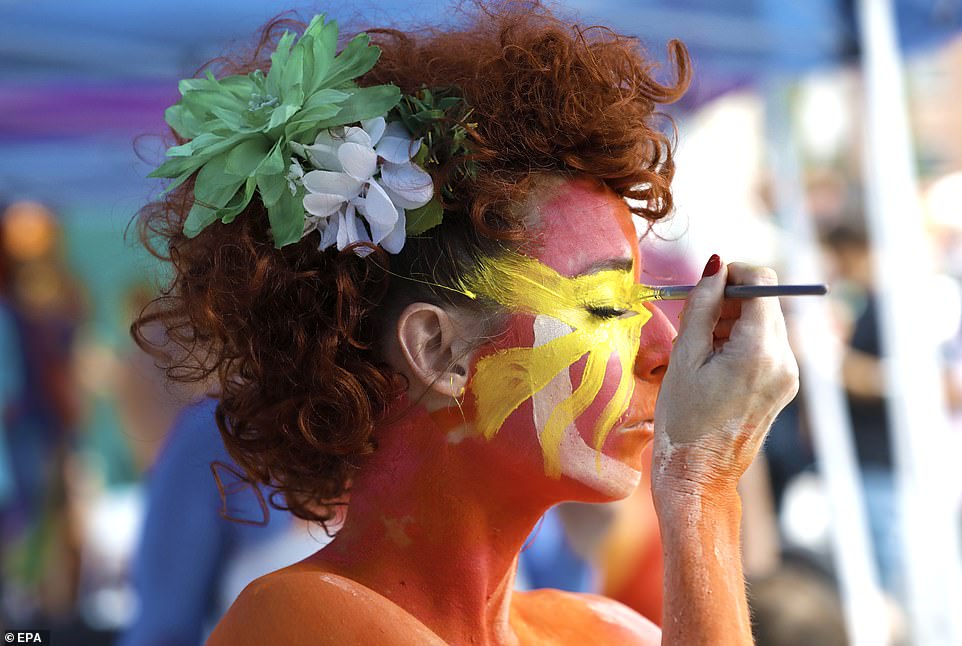 A body painting artist paints her face in Union Square at the 8th annual NYC National Body Painting Day event in New York