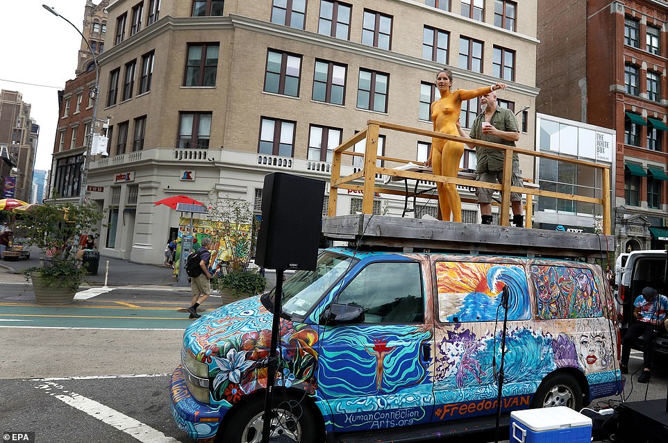 Body painting artist John Rovito (R) paints a model on top of his van in Union Square