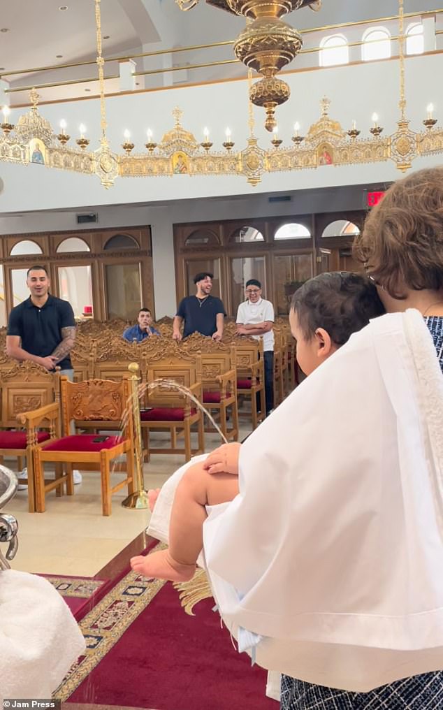 Onlookers are shocked to see the baby start to urinate while being christened by the priest during the ceremony