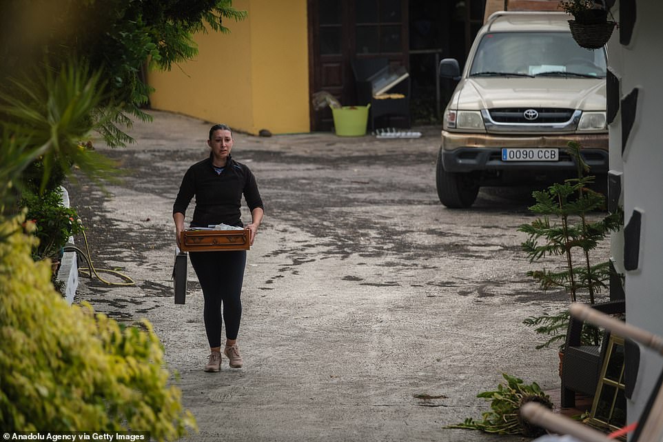 A woman carries a drawer during an evacuation process as Mount Cumbre Vieja continues to erupt in El Paso, spewing out columns of smoke, ash and lava