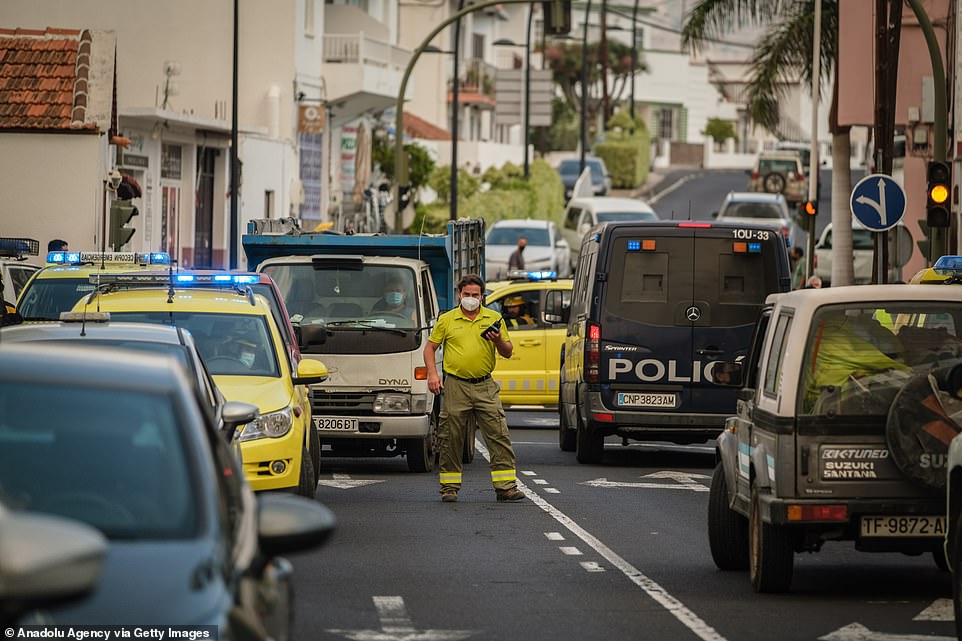Police and fire vehicles are seen on a road in the town of Todoque as residents are evacuated with lava nearing their homes