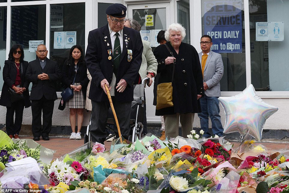 Members of the public including a veteran pay their respects at floral tributes left at the scene of the fatal stabbing