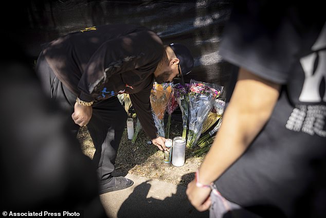 A man places a candle at a memorial in Houston for the victims of the Astroworld music festival on Sunday, Nov. 7, 2021. (AP Photo/Robert Bumsted)