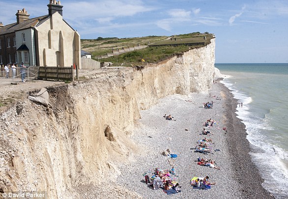 Visitors sunbathe dangerously close on the cliffs at Birling Gap in Sussex, ignoring warnings of cliff falls