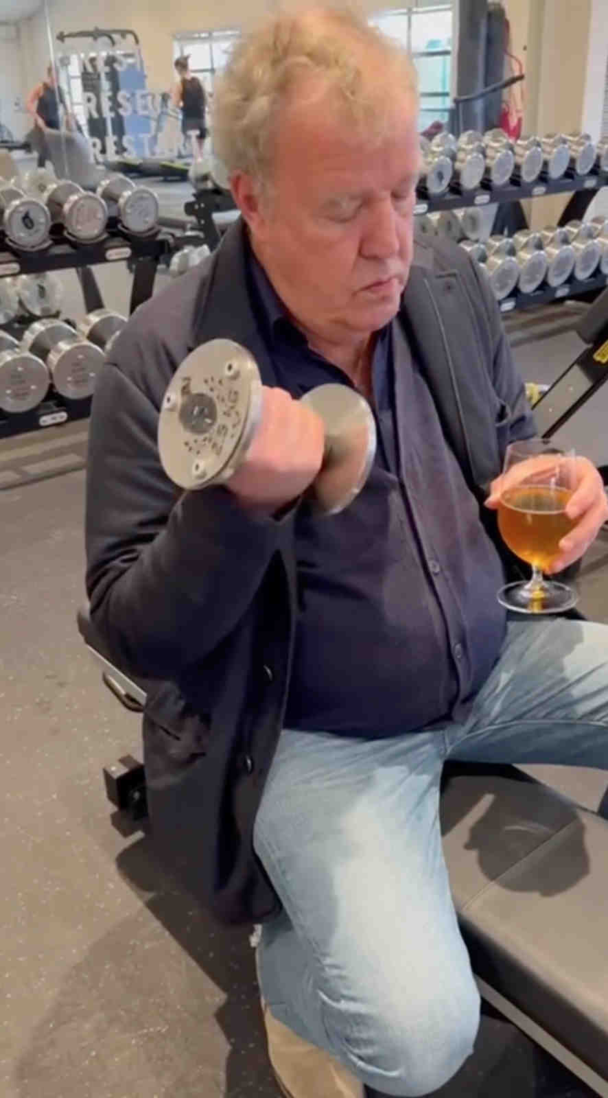 Jezza flexes his muscles in the gym while sipping on a glass of wine